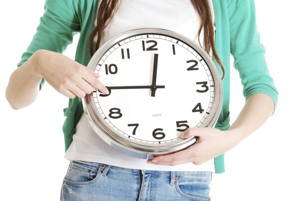 Young casual woman holding clock.